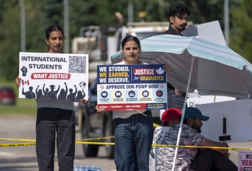 International graduate holding a PGWP refusal letter outside an Alberta college campus